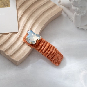 Dettaglio di un fermaglio per capelli in maglia arancione con orsetto di cristallo