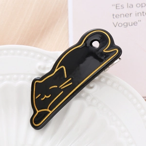 Barrette à cheveux chat noir créative avec contours dorés sur une assiette en céramique