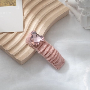 Dettaglio della clip per capelli in maglia rosa con orsetto di cristallo su vassoio