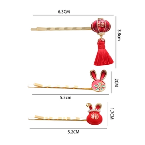 Three Chinese New Year hair clips with rabbit, lucky bag and lantern charms in red and gold