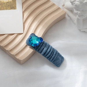 Dettaglio del fermaglio per capelli in maglia blu con decoro a forma di orsetto