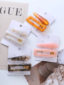 Close-up of acetate hair clips in amber, cream, and pink on stylish fashion magazines