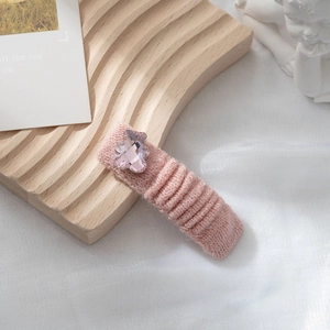 Dettaglio del fermaglio per capelli in maglia rosa con decoro a forma di orsetto di cristallo