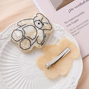 Set de barrettes à cheveux ours en acétate marbré présenté sur une assiette élégante