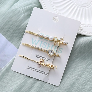 Détail de l'ensemble de barrettes avec lettres Queen, perles et strass sur carte