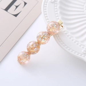 Elegant gold hair clip featuring four resin spheres with pink glitter and gold foil accents