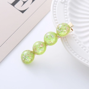 Detail of green resin hair clip with gold foil flakes and four translucent beads