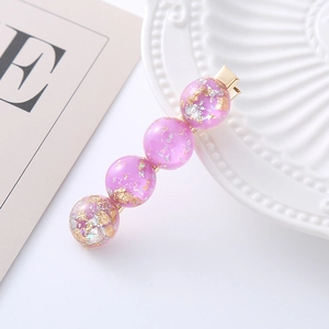Detail of purple resin hair clip with gold foil flakes on a minimalist white ceramic plate