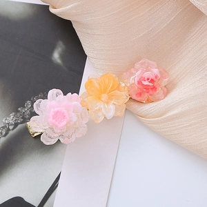 Floral acetate hair clips in pink and yellow hues on a champagne silk background
