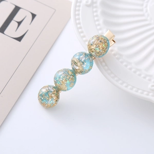 Detail of blue faux opal hair clip with gold foil flakes on a metallic duckbill base