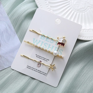 Détail d'un ensemble de trois barrettes dorées avec perles, étoile et astronaute