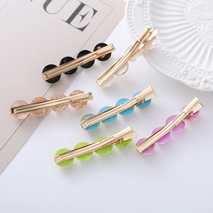 Detail of colorful opal-style hair clips with gold metal base on a white ceramic plate