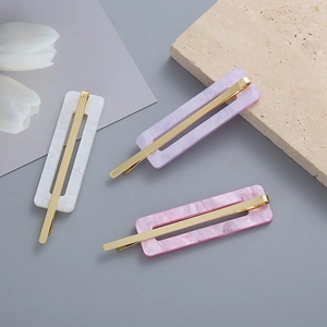 Detailed macro view of geometric acetate hair clips with marble texture and gold metal base