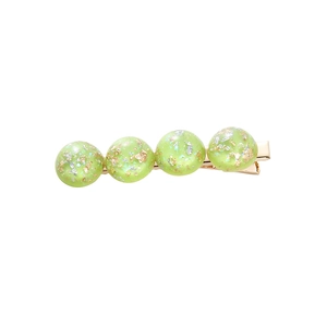 Elegant gold hair clip with four light green resin beads containing sparkling gold foil