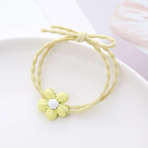 Élastique à cheveux jaune mignon avec petite fleur et nœud papillon sur une assiette blanche