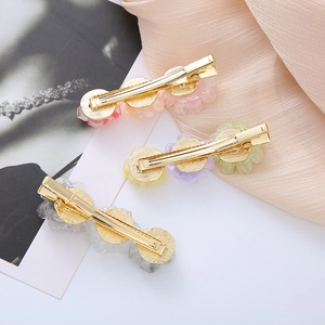 Detailed back view of three floral acetate hair clips with gold metal duckbill fasteners
