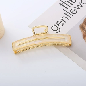 Eleganter champagnergoldener Haarklammer mit Marmor-Acetat auf weißem Tisch