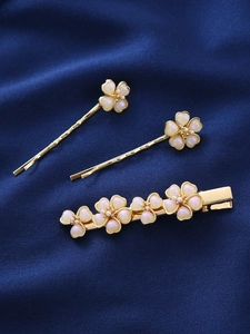 Nahaufnahme goldener Blumenhaarklammern mit Perlen auf blauem Seidenhintergrund
