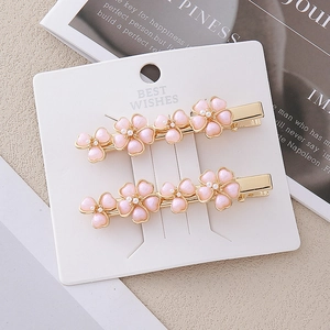 Detail von zweiteiligen rosa Blumen-Haarspangen mit Goldbasis und Perlenzentren