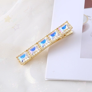 Détail d'une barrette en métal doré avec cinq cristaux carrés aux reflets irisés
