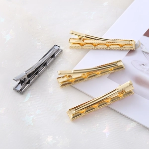 Lot de quatre barrettes à cheveux en métal texturé doré et gris anthracite sur tulle blanc