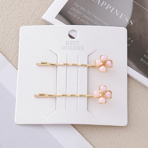 Detailansicht von zwei goldenen Blumen-Haarspangen mit rosa Blüten und weißen Perlen