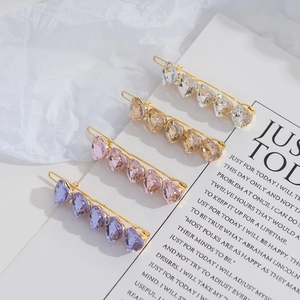 Detailed close-up of heart-shaped crystal hair clips in four elegant gradient colors
