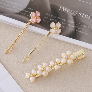 Detailansicht eleganter Haarspangen mit rosa-weißen Blumen, Perlen und goldener Legierung