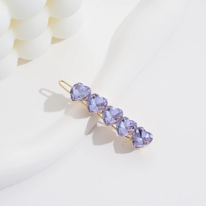 Elegant gold metal hair clip featuring five purple faceted crystal hearts on white stand