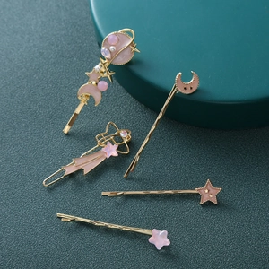 Dettaglio di set di 5 fermagli per capelli rosa e oro con motivi di stelle e luna