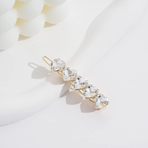 Elegant gold metal hair clip featuring five clear heart-shaped crystals on white background