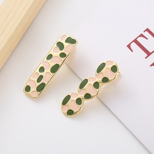 Detail view of French vintage hair clips with green and pink enamel patterns and gold trim