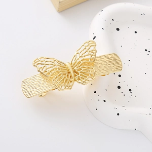 Detail of a hollow golden butterfly hair clip featuring rhinestones and a textured base clip
