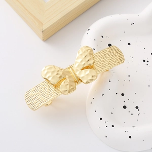 Elegant gold metal bow hair clip with hollow butterfly design on a minimalist background