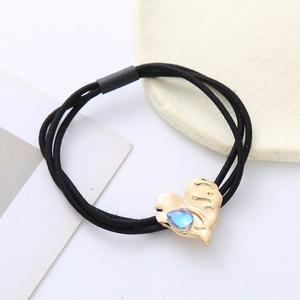 Macro detail of elastic hair tie with gold heart charm and blue crystal stone inlay