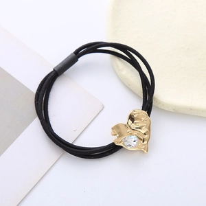 Close-up of triple-strand black hair tie with gold heart-shaped lava crystal detail