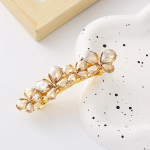 Detail of a golden bow hair clip featuring champagne teardrop crystals and alloy base