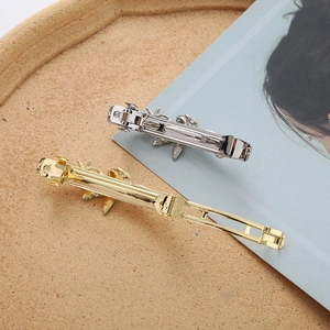 Detail of gold and silver leaf-shaped metal spring hair clips on a wooden tray