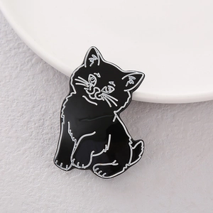Macro shot of a cute minimalist black cat enamel hairpin on a white ceramic plate