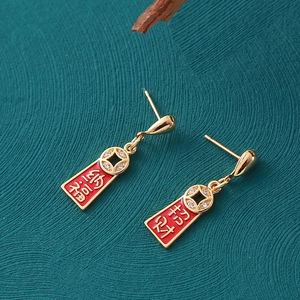 Détails macro de boucles d'oreilles chinoises avec pièces d'or et charms rouges