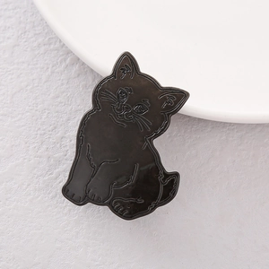 Close-up of a minimalist black and silver cat-shaped hair clip on a textured surface