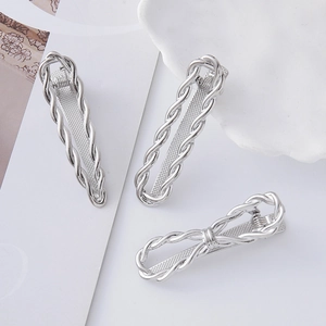 Dettaglio del set di fermagli in metallo argento con texture intrecciata e forma a fiocco
