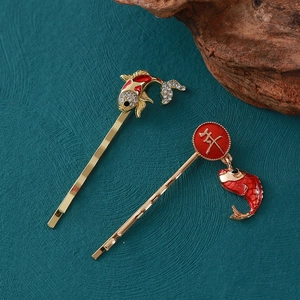 Vue détaillée des barrettes de Nouvel An dorées avec poisson koi et pendentif de l'année