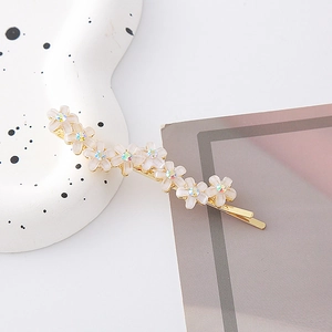 Dettaglio di elegante fermaglio dorato con fiori color crema e cristalli aurora lucidi