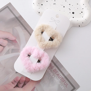 Detailansicht von flauschigen Haarspangen in Herzform in Beige und Rosa auf Karte