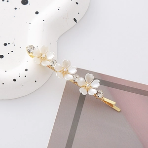 Dettaglio del fermaglio per capelli dorato con fiori di cristallo bianco e strass lucenti