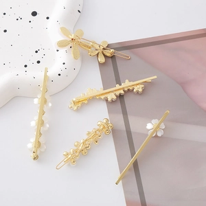 Dettaglio di fermagli per capelli dorati con delicati petali di fiori bianchi e cristalli