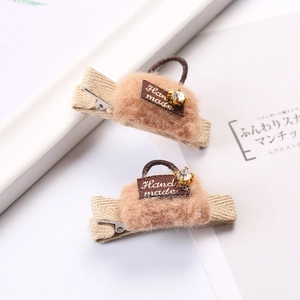 Pair of plush bag-shaped hair clips with 'Hand made' label and sparkling rhinestone