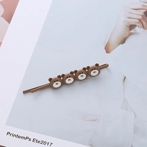 Détail d'une pince à cheveux mate marron avec quatre têtes d'ours 3D sur un magazine