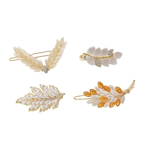 Détails de quatre barrettes dorées en forme de feuille avec perles et cristaux